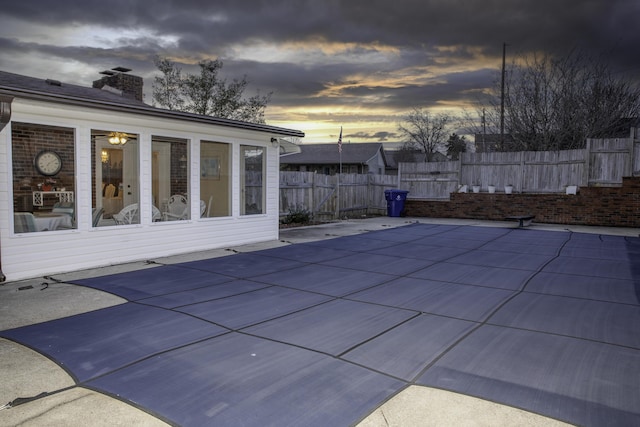 pool at dusk featuring a patio area