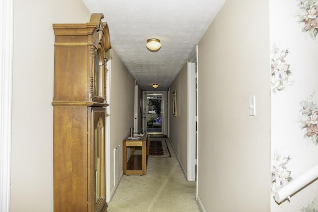 corridor featuring light carpet and a textured ceiling