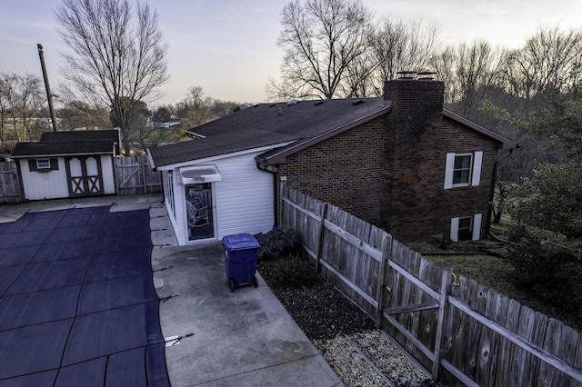 property exterior at dusk with a patio and a shed