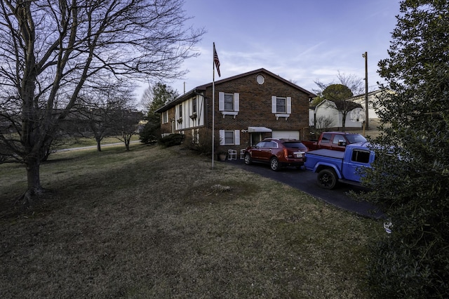 view of side of property featuring a garage and a lawn