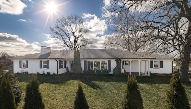 ranch-style home featuring a chimney and a front lawn