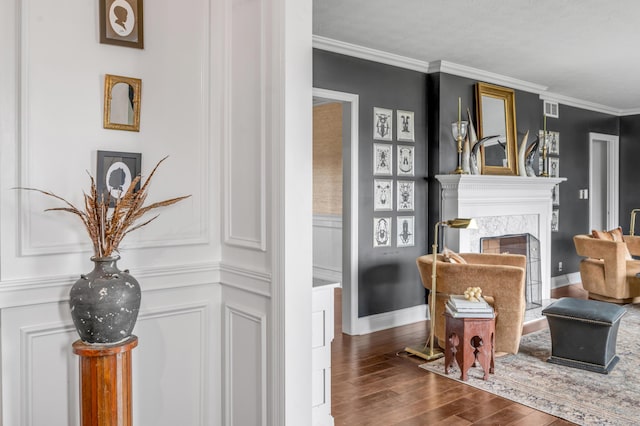 living area featuring a decorative wall, a premium fireplace, wood finished floors, visible vents, and ornamental molding