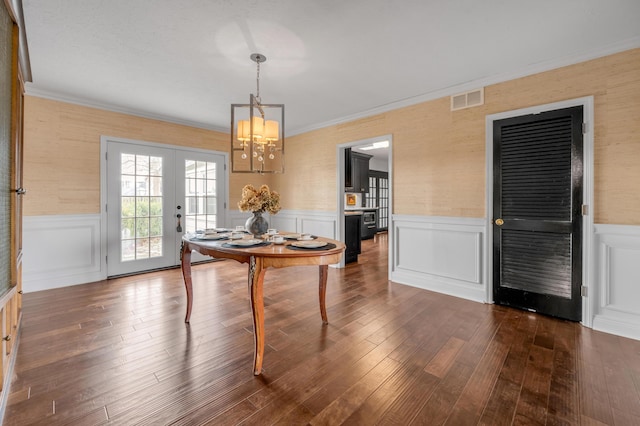 dining area featuring dark wood-style flooring, visible vents, a wainscoted wall, and french doors