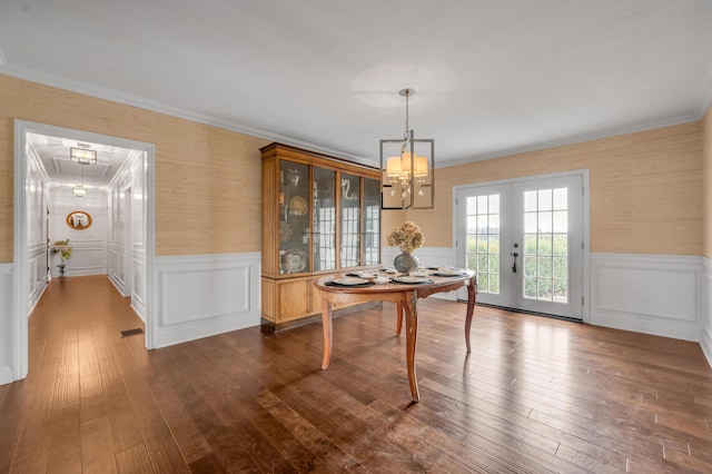 dining area with french doors, dark wood-style flooring, crown molding, attic access, and wainscoting