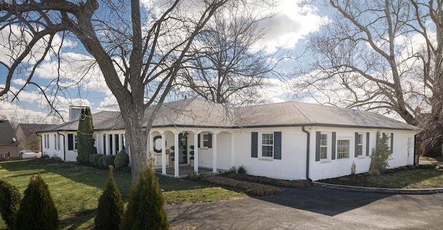 single story home featuring stucco siding, a chimney, and a front yard