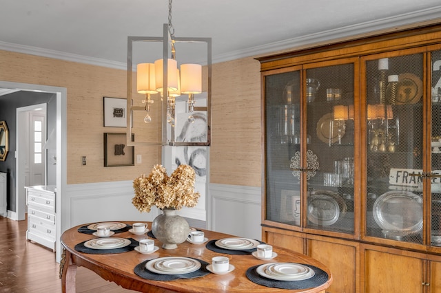 dining area featuring a wainscoted wall, ornamental molding, and dark wood-style floors