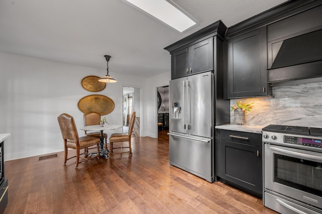 kitchen with extractor fan, visible vents, appliances with stainless steel finishes, hardwood / wood-style floors, and tasteful backsplash