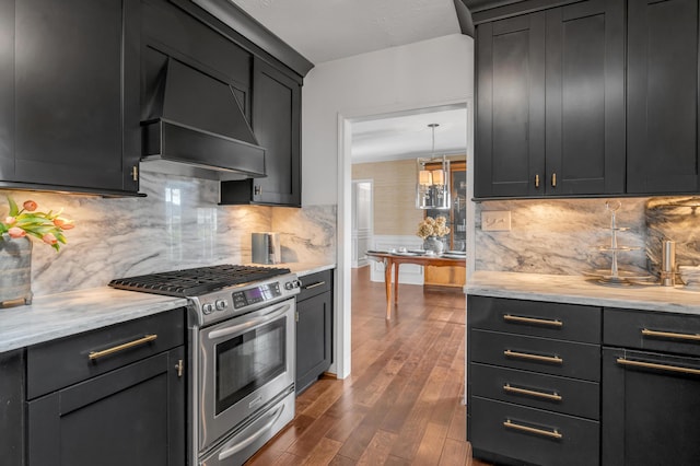 kitchen featuring dark wood-style floors, backsplash, stainless steel range with gas cooktop, and custom range hood