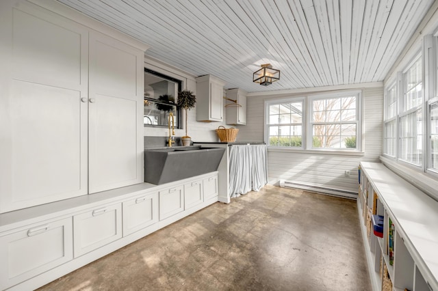 unfurnished sunroom with a sink, a baseboard radiator, and a wealth of natural light