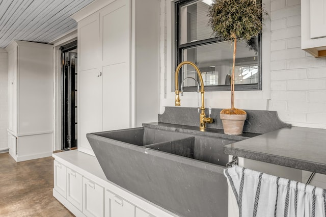 interior space featuring concrete block wall, concrete floors, and a sink