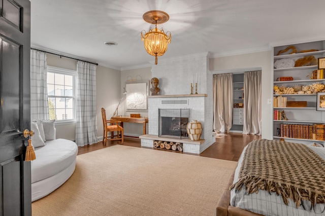 bedroom featuring visible vents, wood finished floors, an inviting chandelier, crown molding, and a fireplace