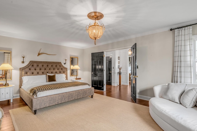 bedroom with a notable chandelier, baseboards, wood finished floors, and crown molding