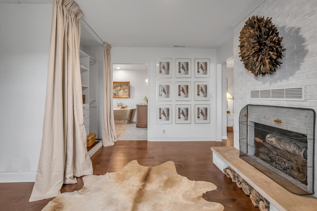 interior space featuring a fireplace, wood finished floors, visible vents, and baseboards