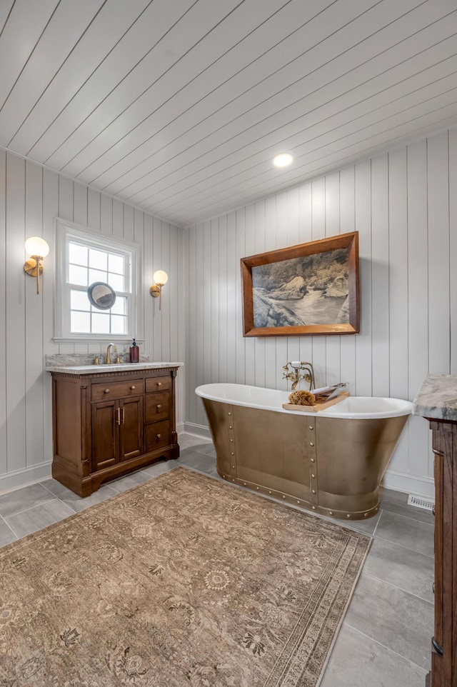 bathroom featuring a freestanding tub, vanity, and baseboards