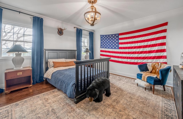 bedroom with ornamental molding, baseboards, an inviting chandelier, and wood finished floors