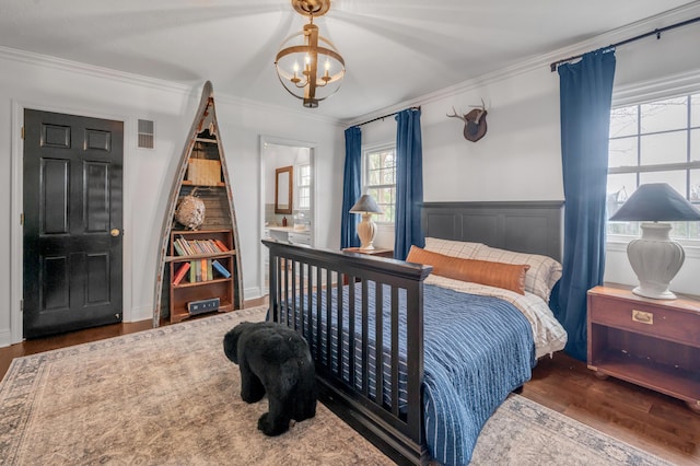 bedroom with a wainscoted wall, crown molding, wood finished floors, and an inviting chandelier