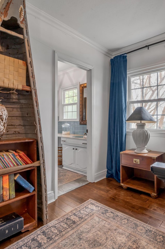 interior space with ornamental molding, wood finished floors, and baseboards