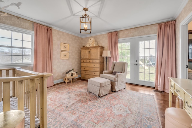 bedroom with a notable chandelier, wood finished floors, french doors, wallpapered walls, and crown molding