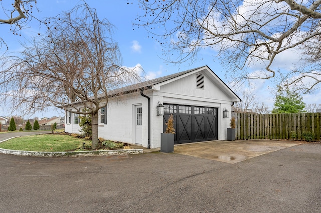 view of side of property with an attached garage, fence, aphalt driveway, and a lawn