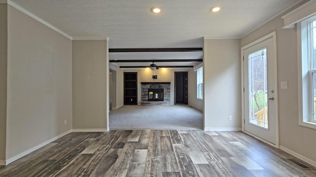 unfurnished living room featuring crown molding, a stone fireplace, and a wealth of natural light