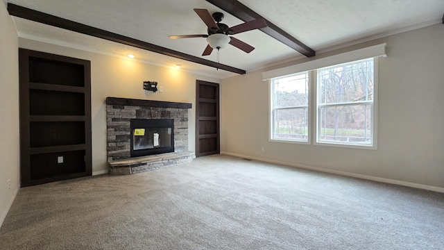 unfurnished living room featuring ceiling fan, beam ceiling, carpet flooring, a fireplace, and built in shelves