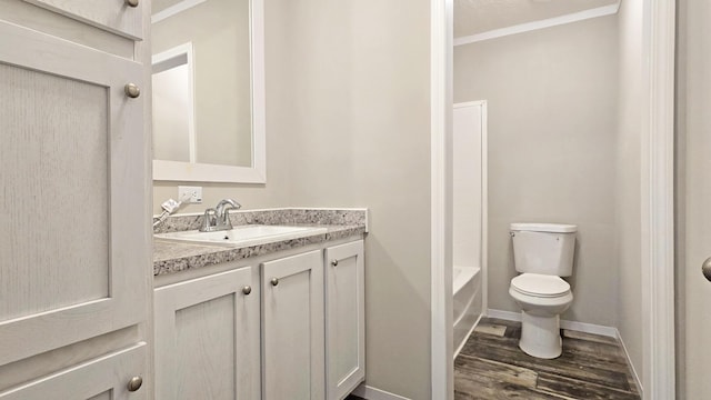 full bathroom featuring hardwood / wood-style floors, vanity, ornamental molding, shower / washtub combination, and toilet