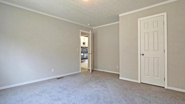 carpeted spare room featuring crown molding and a textured ceiling