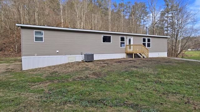 rear view of house with cooling unit and a lawn