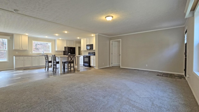 kitchen with a kitchen island, white cabinetry, a kitchen breakfast bar, ornamental molding, and black appliances