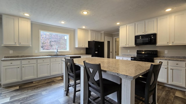 kitchen featuring white cabinetry, a center island, sink, and black appliances