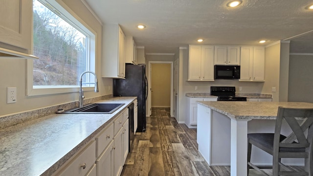 kitchen featuring dark wood-type flooring, sink, a breakfast bar area, white cabinetry, and black appliances