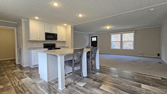 kitchen featuring white cabinetry, ornamental molding, a kitchen breakfast bar, a kitchen island, and black appliances