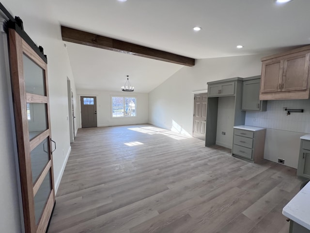 kitchen featuring tasteful backsplash, lofted ceiling with beams, an inviting chandelier, a barn door, and light wood-type flooring