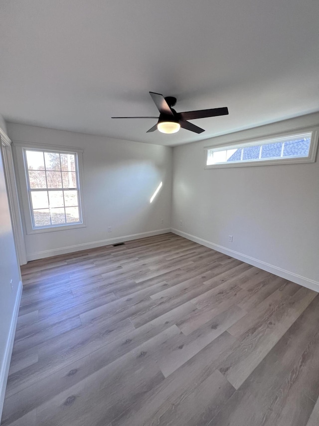 empty room with light hardwood / wood-style flooring, a wealth of natural light, and ceiling fan