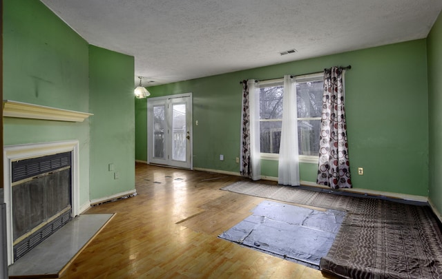 unfurnished living room with hardwood / wood-style flooring and a textured ceiling