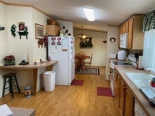 kitchen featuring white appliances, decorative light fixtures, and light wood-type flooring