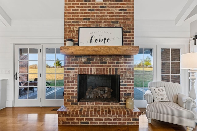 interior space with beam ceiling, hardwood / wood-style floors, a fireplace, and wood walls