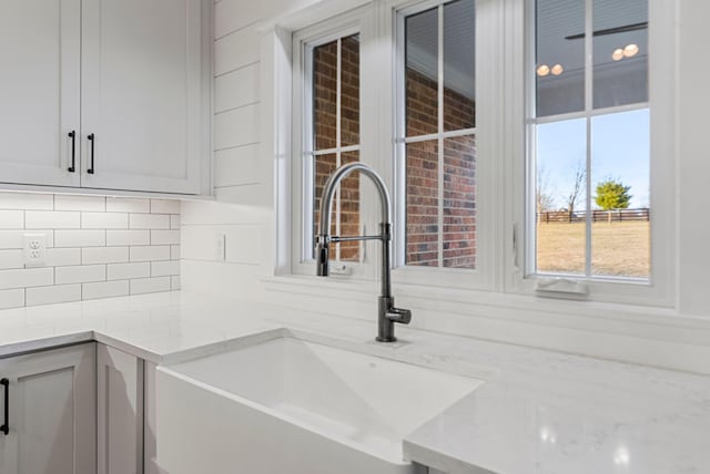 room details featuring light stone counters, sink, and backsplash