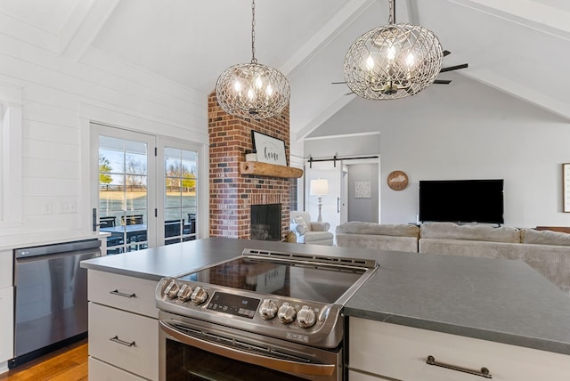 kitchen featuring white cabinets, hanging light fixtures, stainless steel appliances, a barn door, and light hardwood / wood-style flooring