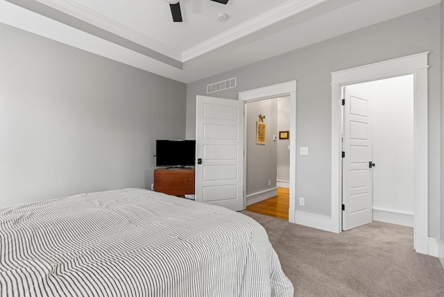 carpeted bedroom featuring ceiling fan, ornamental molding, and a raised ceiling