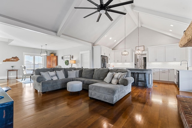 living room featuring ceiling fan with notable chandelier, dark wood-type flooring, high vaulted ceiling, and beamed ceiling