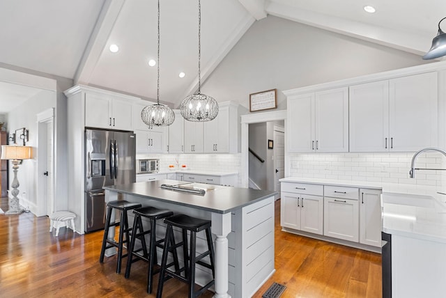 kitchen featuring hanging light fixtures, stainless steel appliances, white cabinets, and a kitchen island