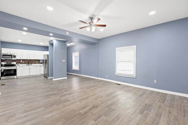 unfurnished living room with ceiling fan, sink, and light hardwood / wood-style floors