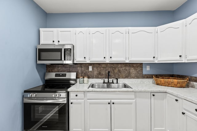 kitchen featuring tasteful backsplash, appliances with stainless steel finishes, sink, and white cabinets