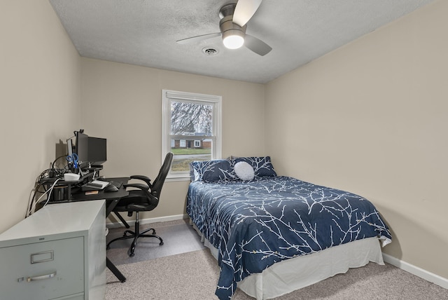 carpeted bedroom with ceiling fan and a textured ceiling