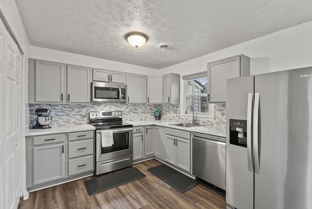 kitchen featuring dark hardwood / wood-style flooring, sink, backsplash, and stainless steel appliances