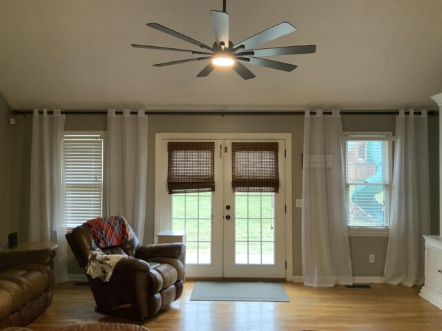 living room with ceiling fan, a high ceiling, and light wood-type flooring