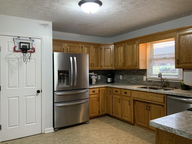 kitchen with tasteful backsplash, stainless steel appliances, sink, and a textured ceiling