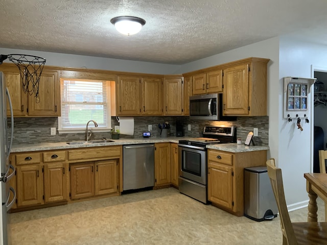 kitchen featuring light countertops, backsplash, appliances with stainless steel finishes, and a sink