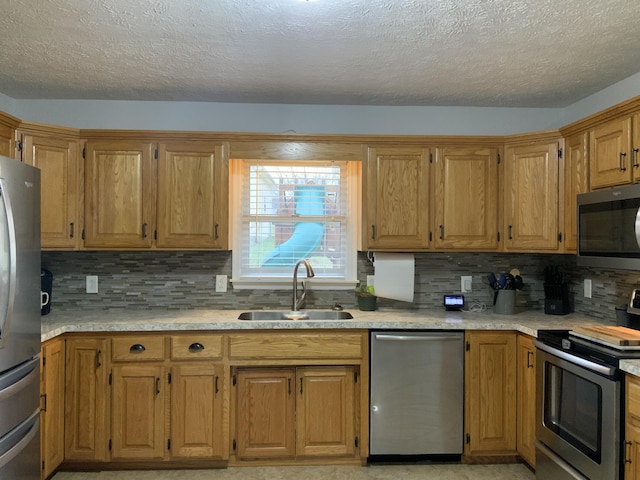 kitchen featuring tasteful backsplash, light countertops, appliances with stainless steel finishes, brown cabinetry, and a sink